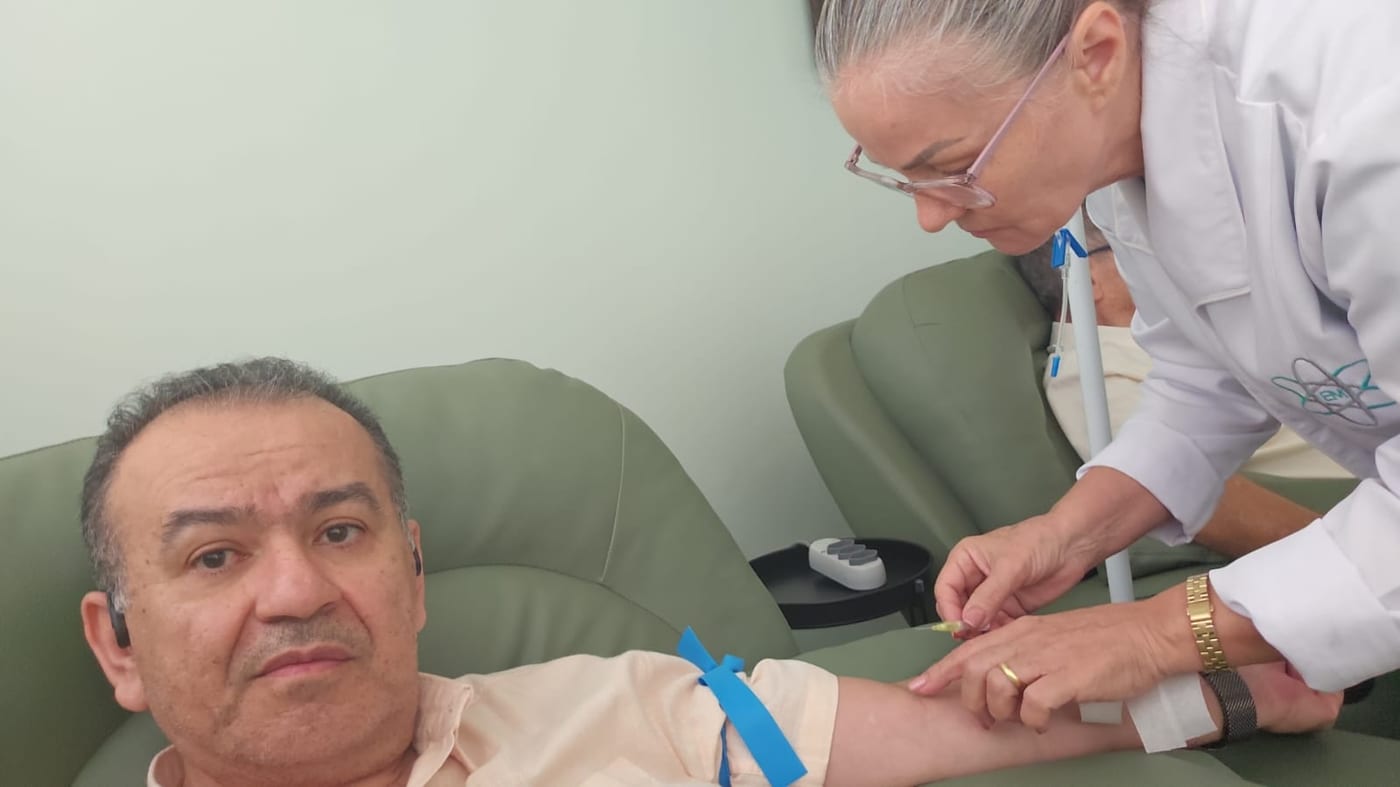 Profissional de enfermagem preparando a punção no braço.
